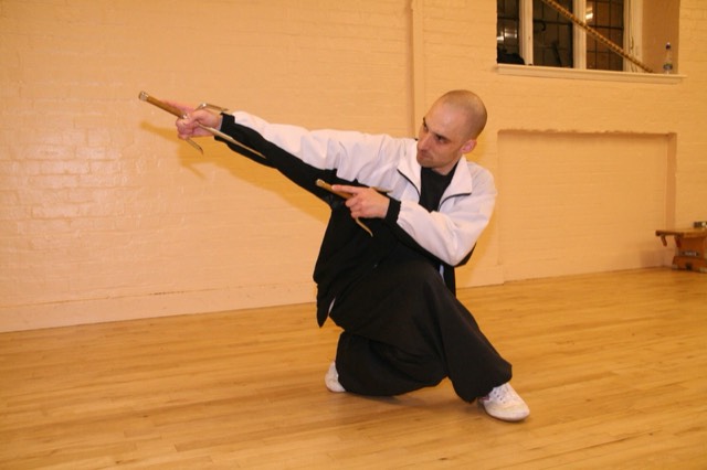 An instructor kneeling in a weapons posture