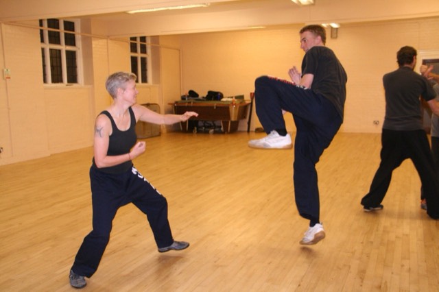 A student lifts his knee to block a strike during sparring