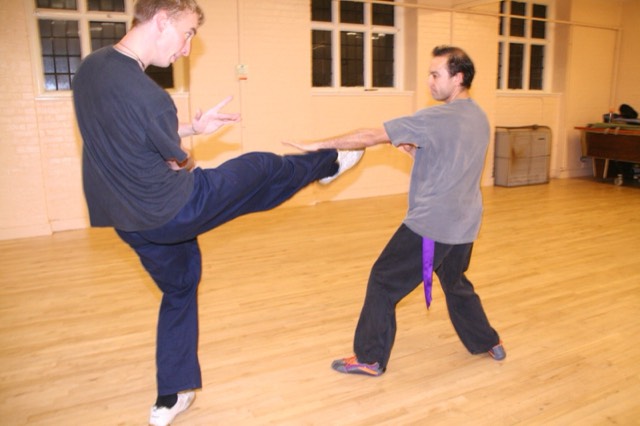 A student kicks while a partner blocks