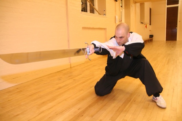 An instructor sweeping a broadsword at floor level