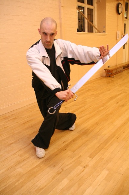 An instructor holding a broadsword in a low guard